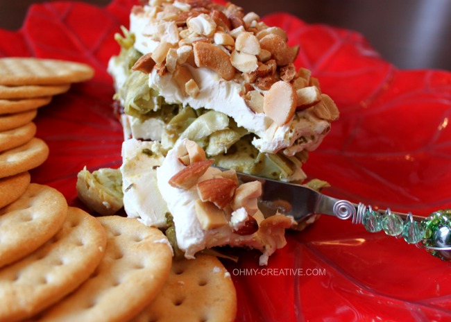 This Layered Sun-dried Tomato and Artichoke Spread Appetizer is easy to make, tasty and perfect for any occasion. The red and green layers make it especially pretty for the holidays! | OHMY-CREATIVE.COM #artichokeappetizer #creamcheeseappetizer #layeredsundriedtomatoartichokespread #artichokespread #pesto 