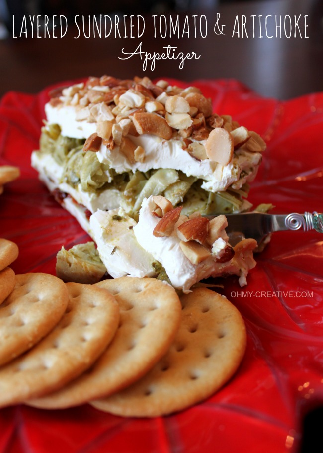This Layered Sun-dried Tomato and Artichoke Spread Appetizer is easy to make, tasty and perfect for any occasion. The red and green layers make it especially pretty for the holidays! | OHMY-CREATIVE.COM #artichokeappetizer #creamcheeseappetizer #layeredsundriedtomatoartichokespread #artichokespread #pesto 