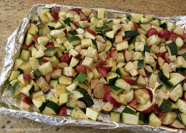A foil lined cookie sheet with chopped Potatoes And Zucchini ready to go in the oven