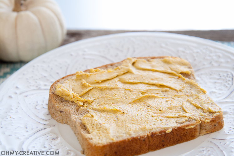 A slice of bread on a white plate with pumpkin spice honey butter on top