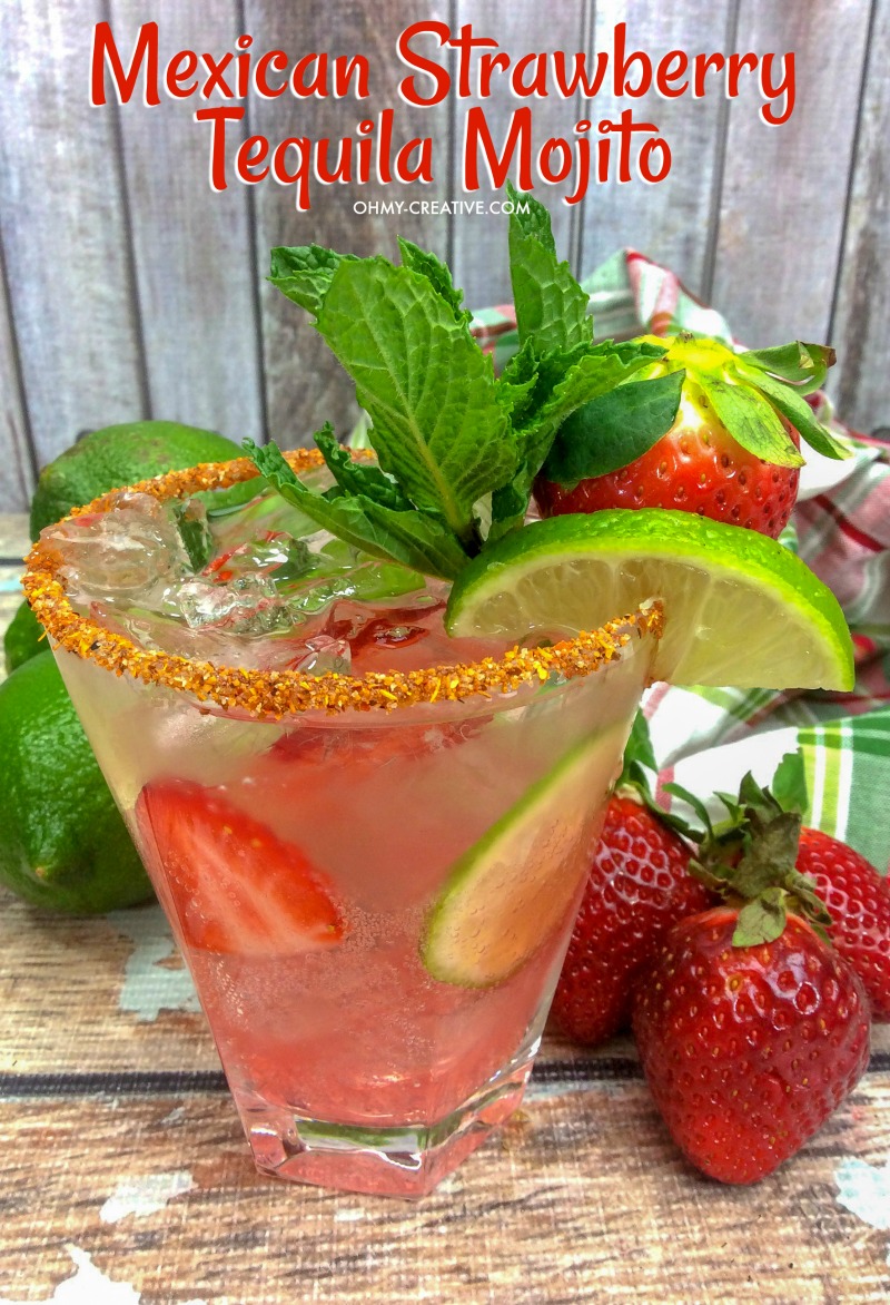 Mexican Strawberry Tequila Mojito garnished with a lime. Whole limes and strawberries sit around the glass