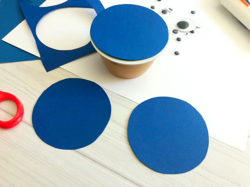 Trace blue paper and cut out circles to make sharks for the applesauce cups. 