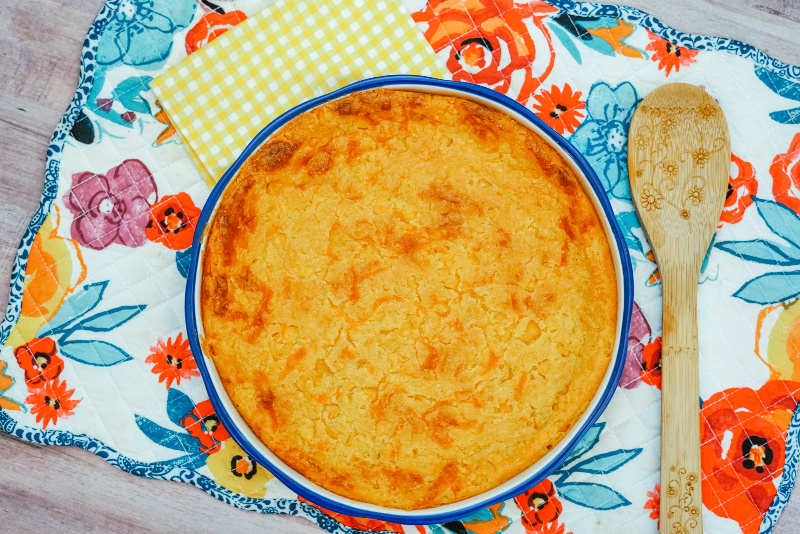 Round corn casserole with Jiffy baked on a placemat. Perfect for weeknight meals or a holiday side dish.