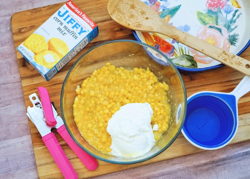 mixing bowl with two kinds of corn and sour cream add to be mixed together for corn casserole