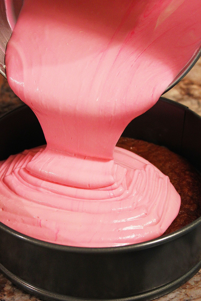 Pour pink peppermint cheesecake filling on top of brownie crust in a spring form pan.