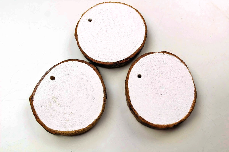 Wood Slices painted white with holes drilled for string to complete showman ornament