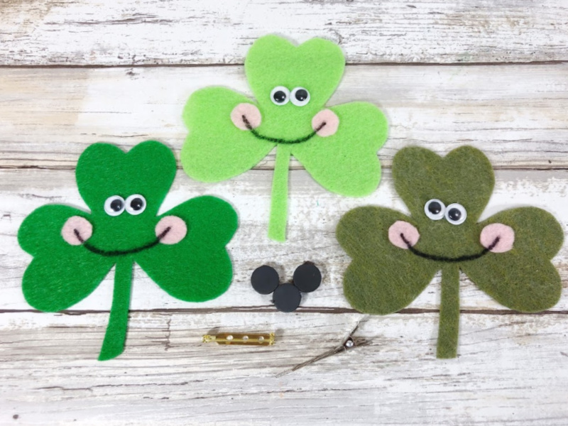 Finished felt shamrock craft with smiling faces and googly eyes. Options to add pin or magnet backing to shamrocks.