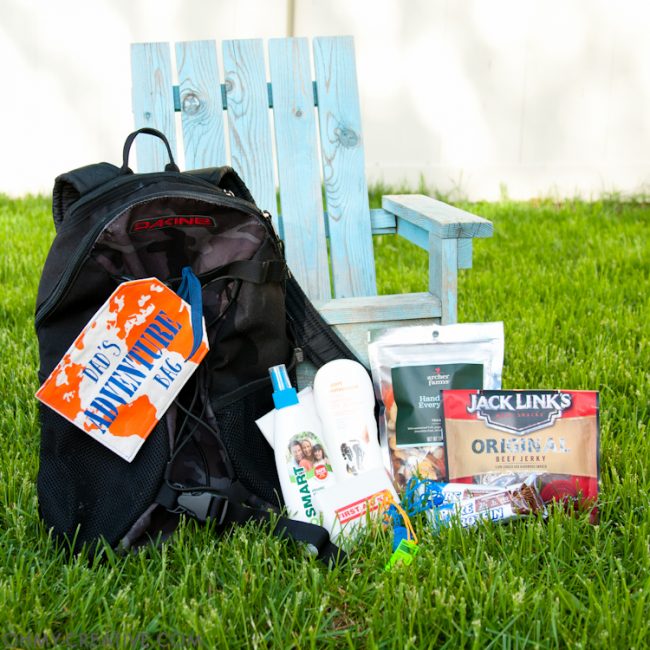 Backpack filled with helpful travel items and adorned with a Father's Day printable tag