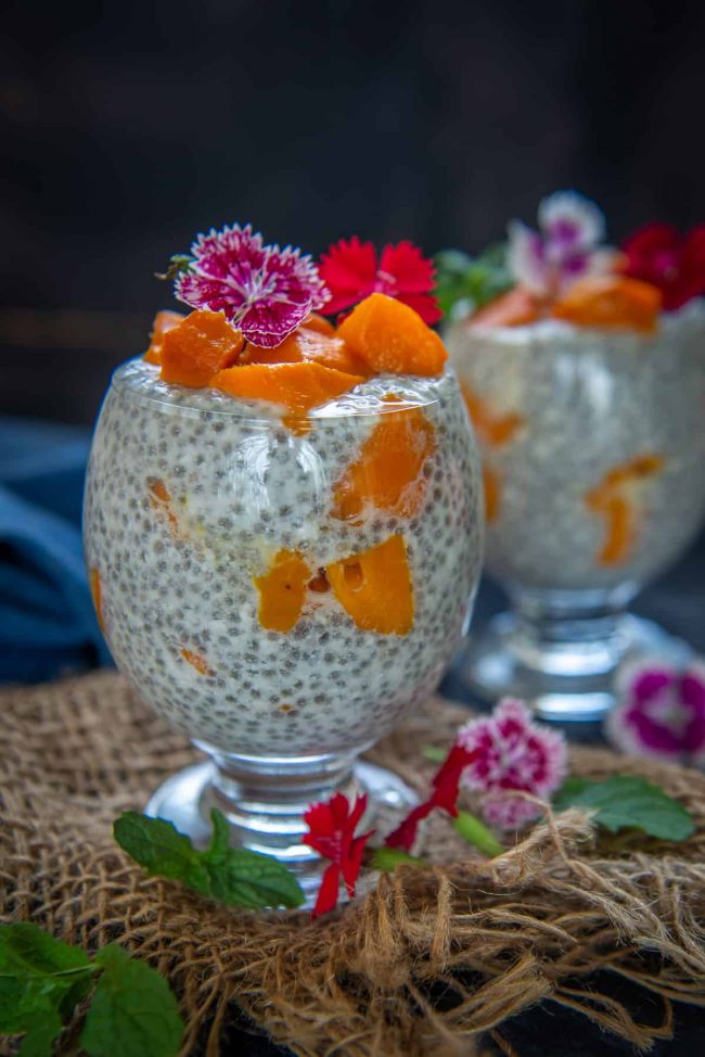 Mango chia pudding decorated with pink tropical flowers.