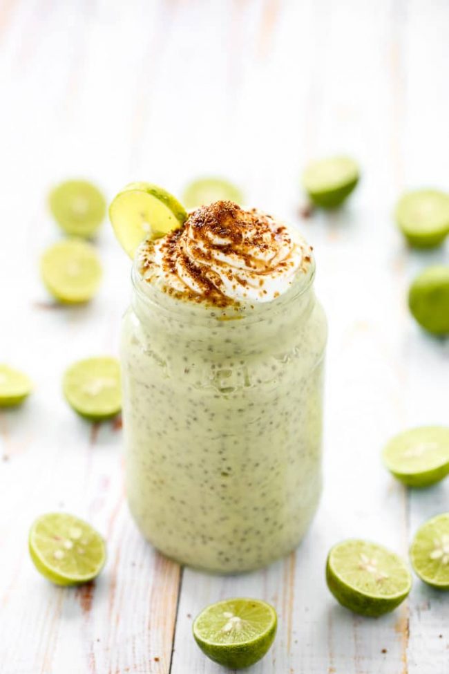 Key lime pie chia pudding on a white wooden background with slices of lime around the pudding.