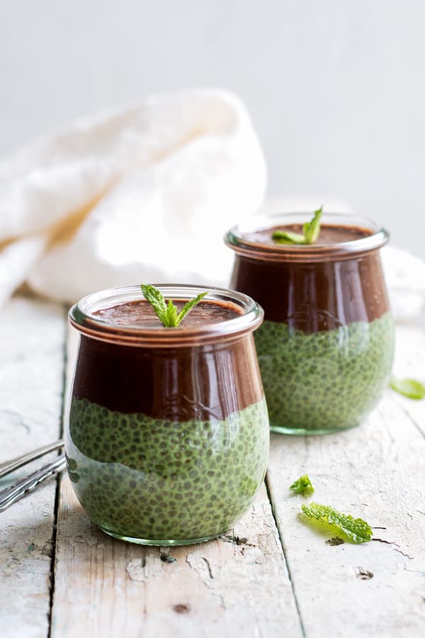 Two Chocolate mint chia puddings on a white wooden table top.. 