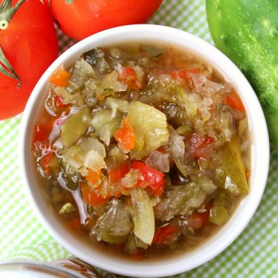 A bowl of sweet pickle relish surrounded by garden vegetables. Easy to can!