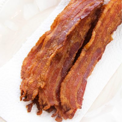 Crispy bacon placed on a paper towel to absorb extra bacon grease.