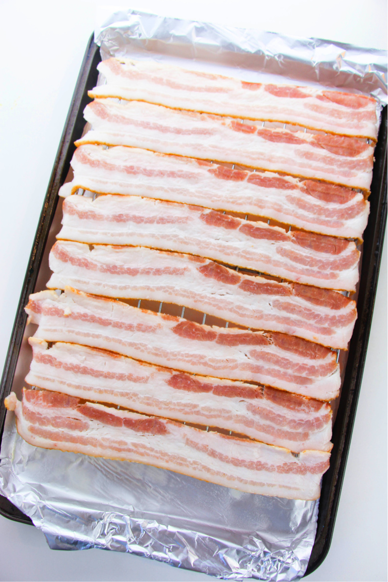 Uncooked bacon on a baking pan ready to go in the oven.