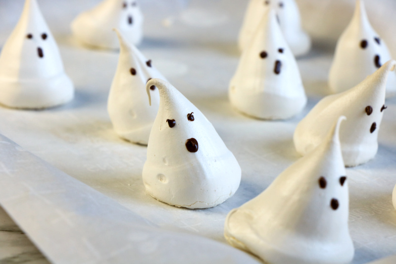 These ghost meringues are finish hardening on parchment paper on the cookie sheet.