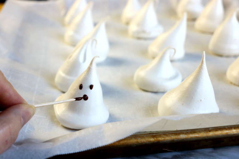 After the ghost meringues are hardened, use the melted chocolate chips to decorate the mouth and eyes with a toothpick.
