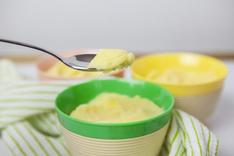Three colorful bowls with a half of cup portion of healthy Dole whip. The green bowl in the has a spoon of Dole whip lifted out of the bowl focusing on a bite of Dole whip. 
