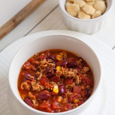 A white bowl filled with weight watchers turkey chili and a small bowl of oyster crackers.