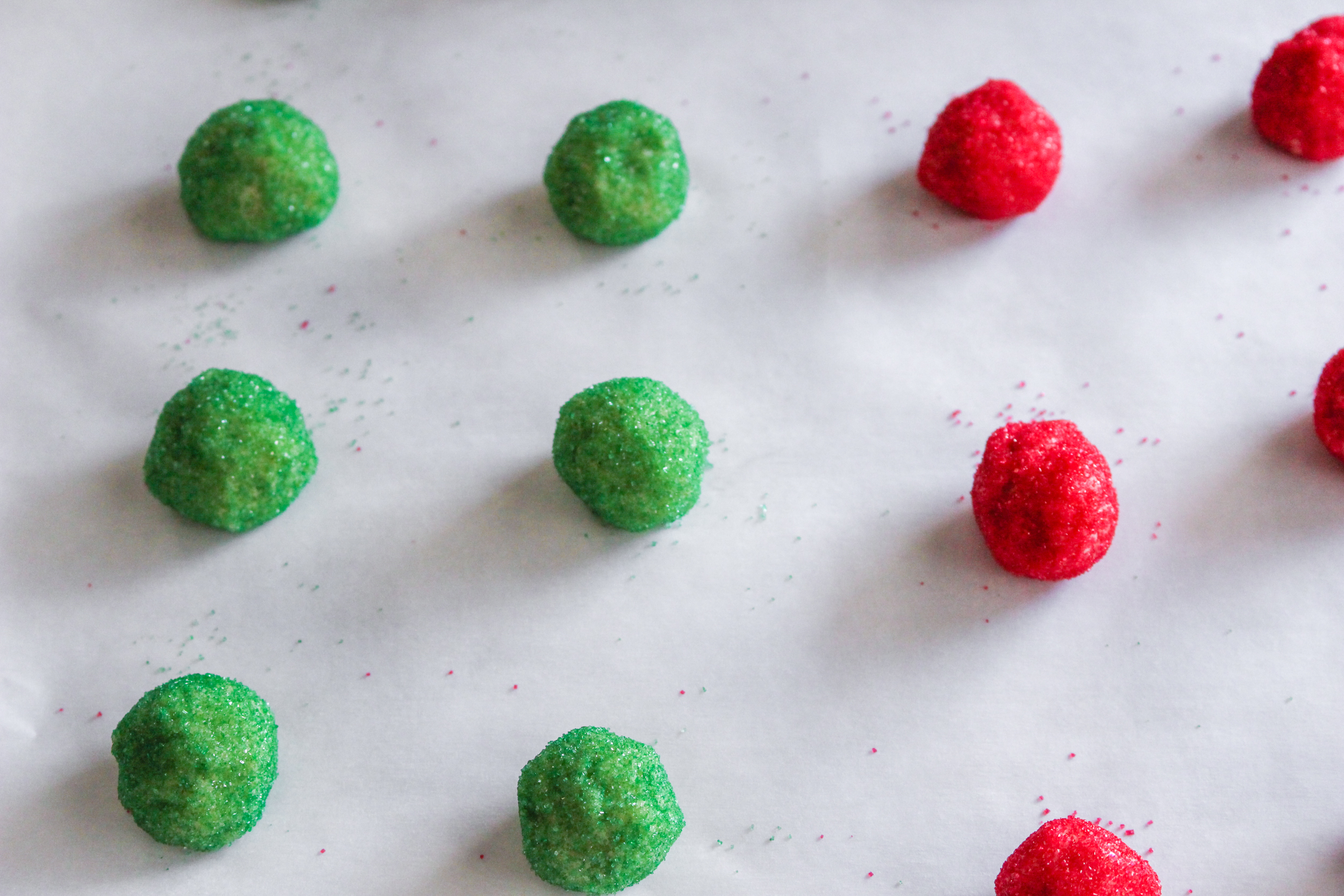 Space out green and red sprinkle dough balls on a cookie sheet to bake.