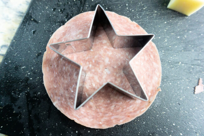 Using a cookie cutter to cut a star out of salami 
