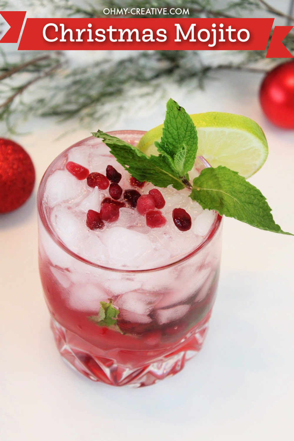 Pretty Christmas mojito cocktail on a white background topped with pomegranate arils. 