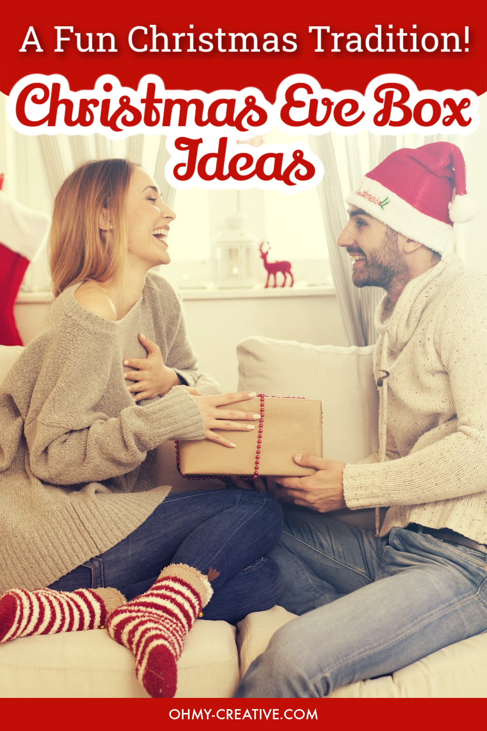 A man and women sitting on the couch laughing holding a Christmas Eve box gift.