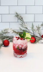 Christmas Mojito on a white background with Christmas greens and small red ornaments in the background.
