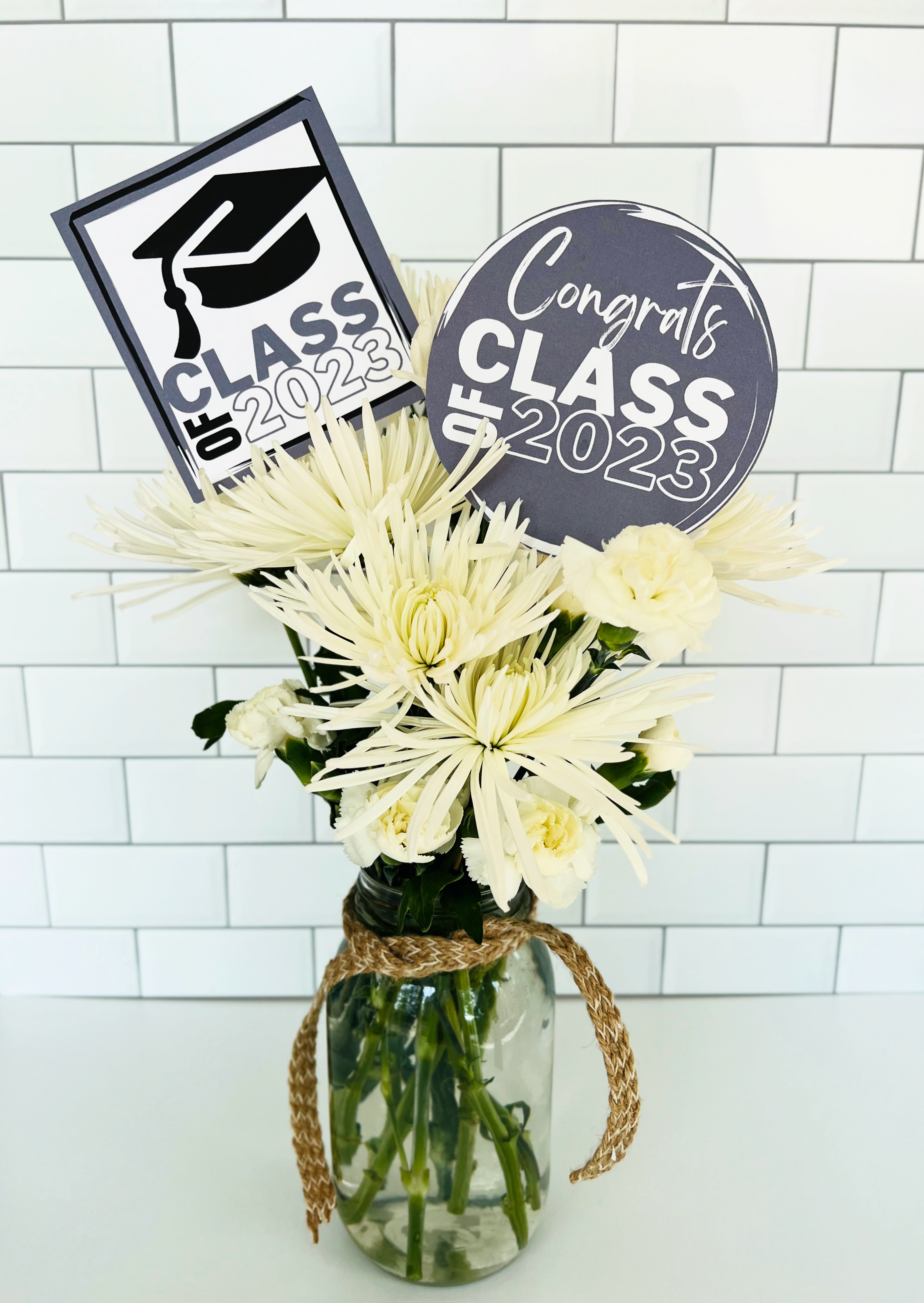 A vase of white flowers with gray and white graduation party printable decorations.