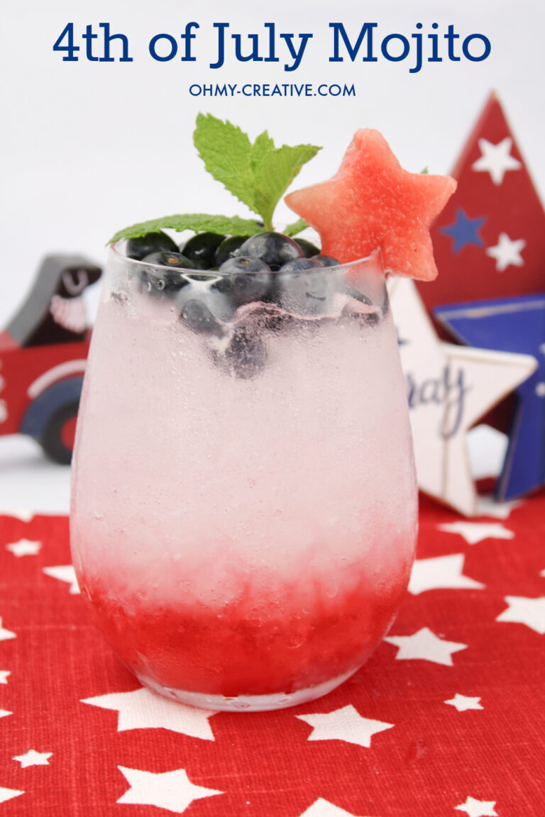 An easy 4th of July Mojito recipe with red raspberries on the bottom, club soda and rum topped with blueberries. A watermelon star and mint garnish this pretty patriotic drink!