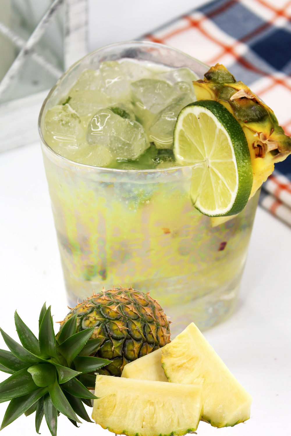 This pineapple mojito is garnished with a slice of lime and fresh pineapple. Also, in the photo is a whole pineapple and additional pineapple chunks.