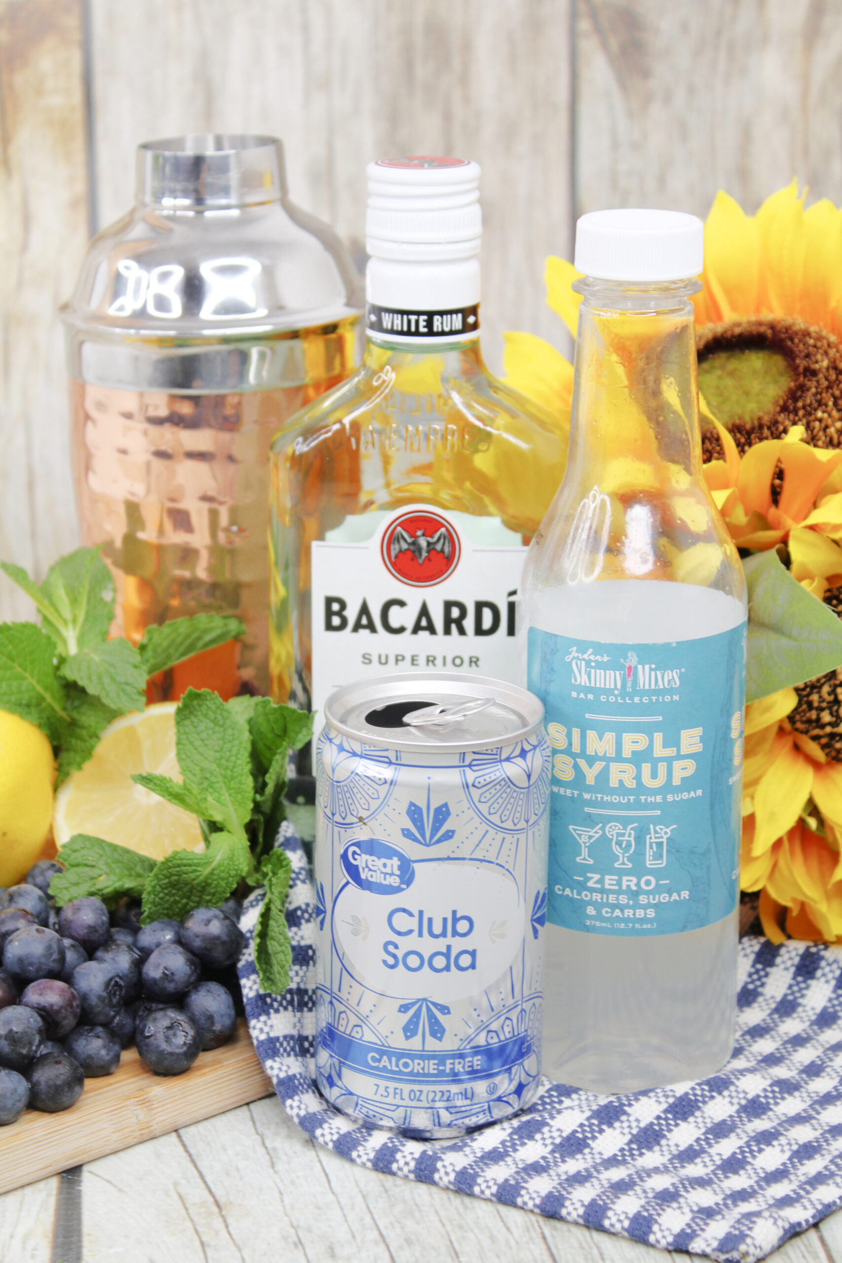 All the ingredients to make a blueberry lemonade mojito with garnishes of mint and sliced lemon!