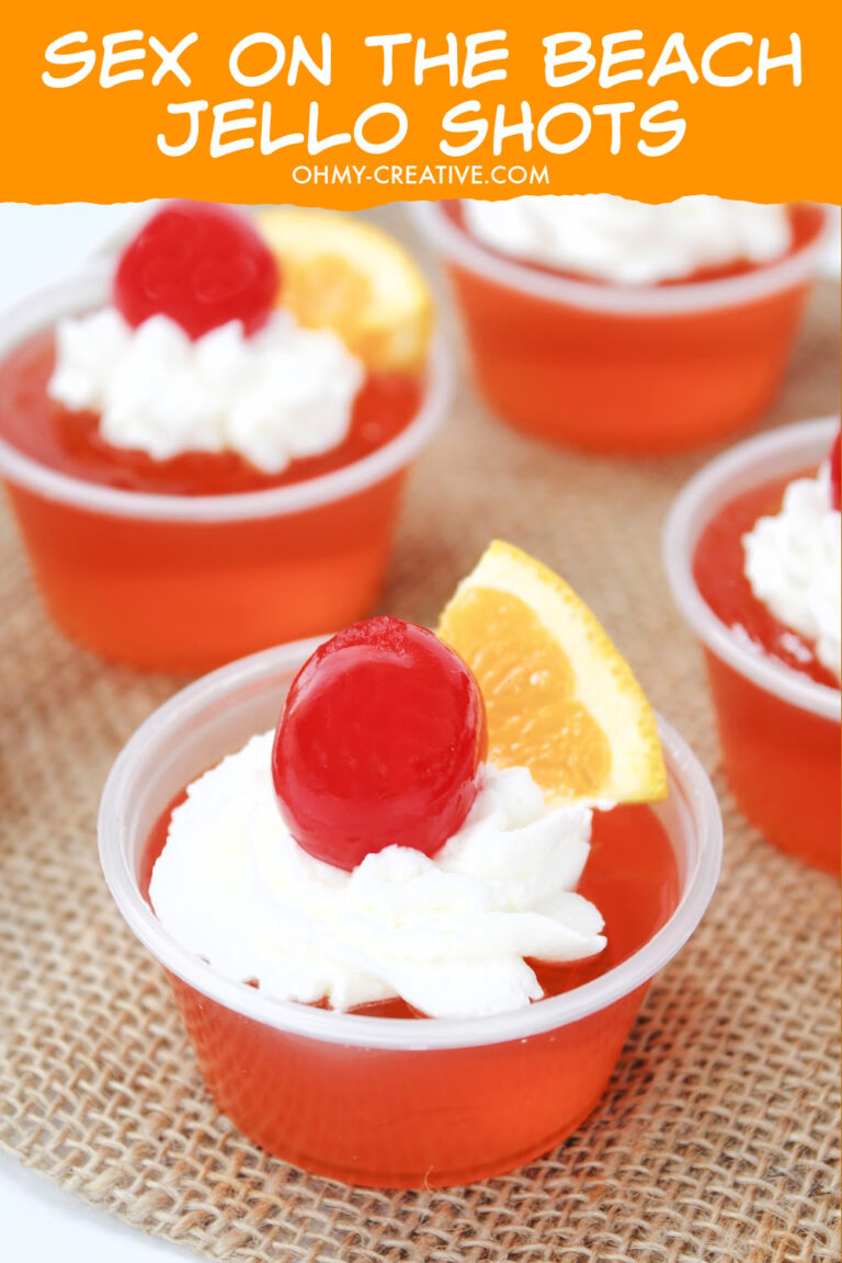 Orange jello shots - sex on the beach jello shots garnished with whipped cream, a cherry and orange wedge on a burlap background.