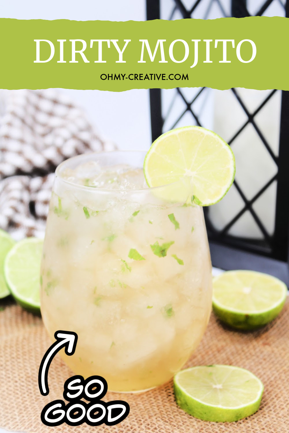 This dirty mojito cocktail is sitting on a burlap background with a black and white checked napkin and a black summer lantern. Garnished include slices of lime.