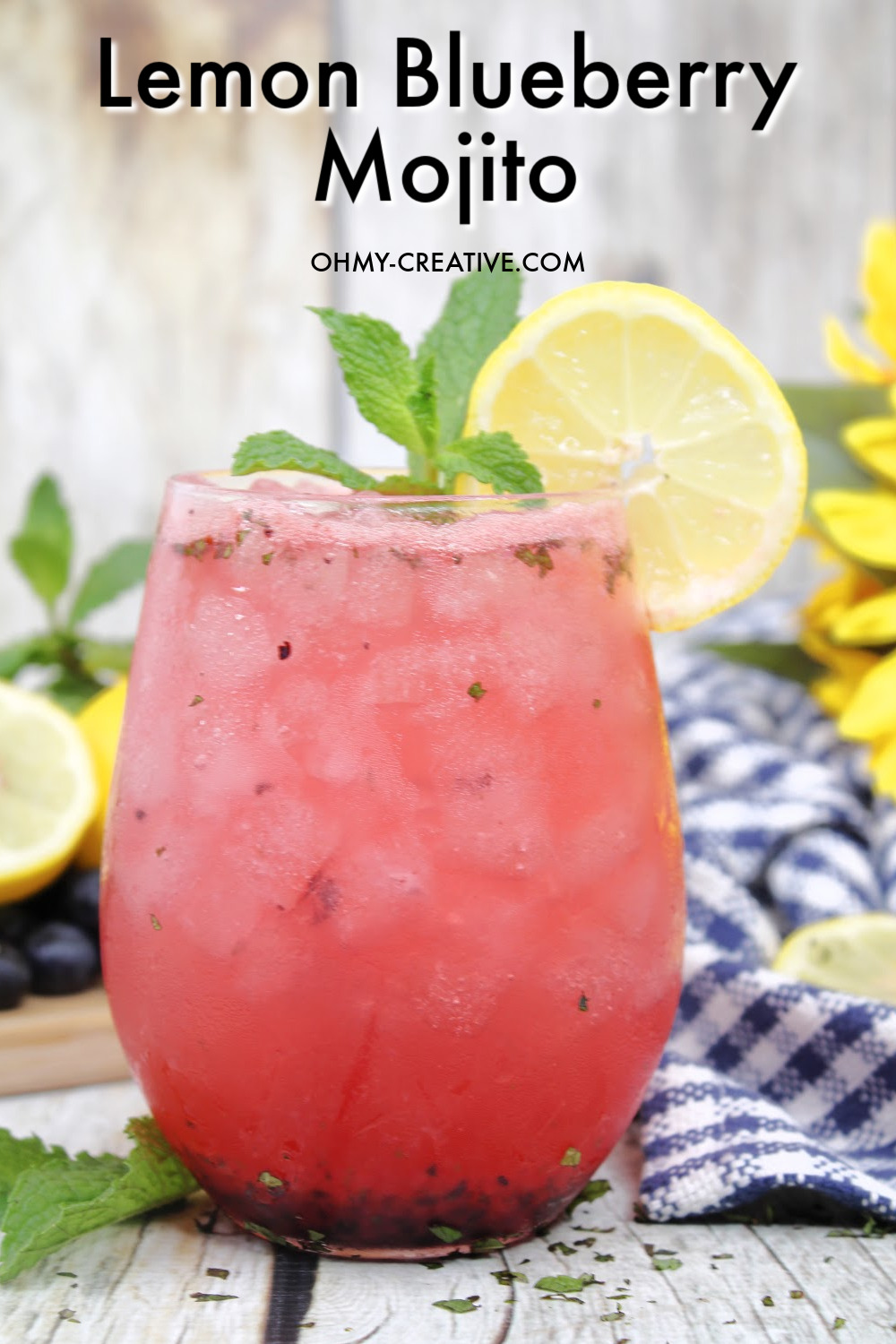 The best flavors of summer are in this blueberry lemonade mojito. Shown here with a blue and white checked napkin with sliced and whole lemons!
