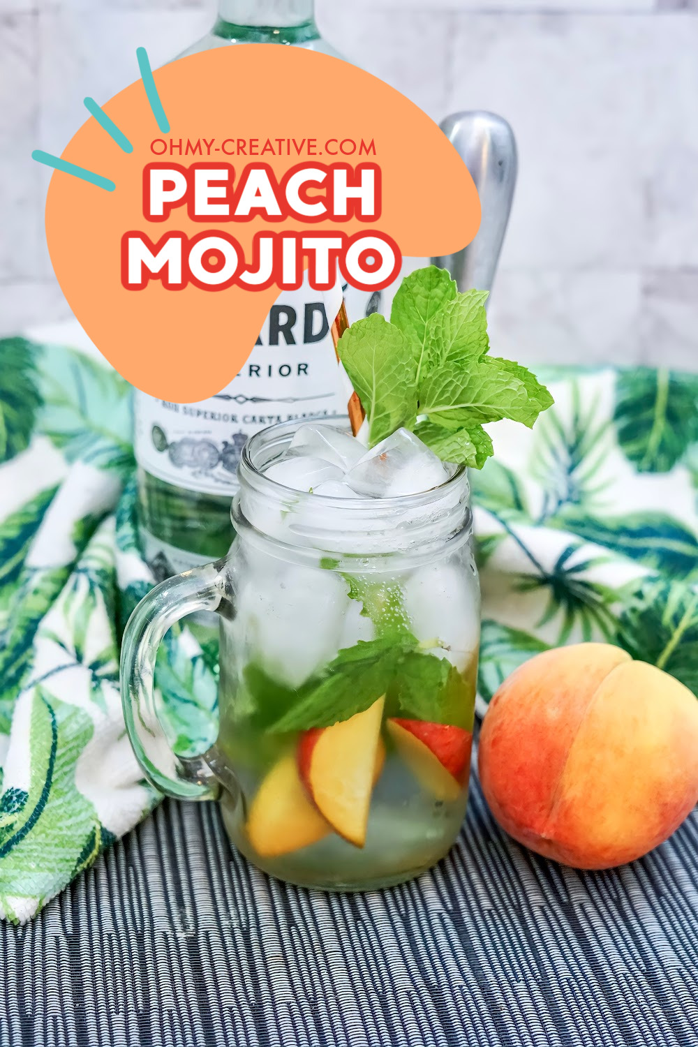 peach mojito cocktail surrounded by fresh peaches served in a mason jar.