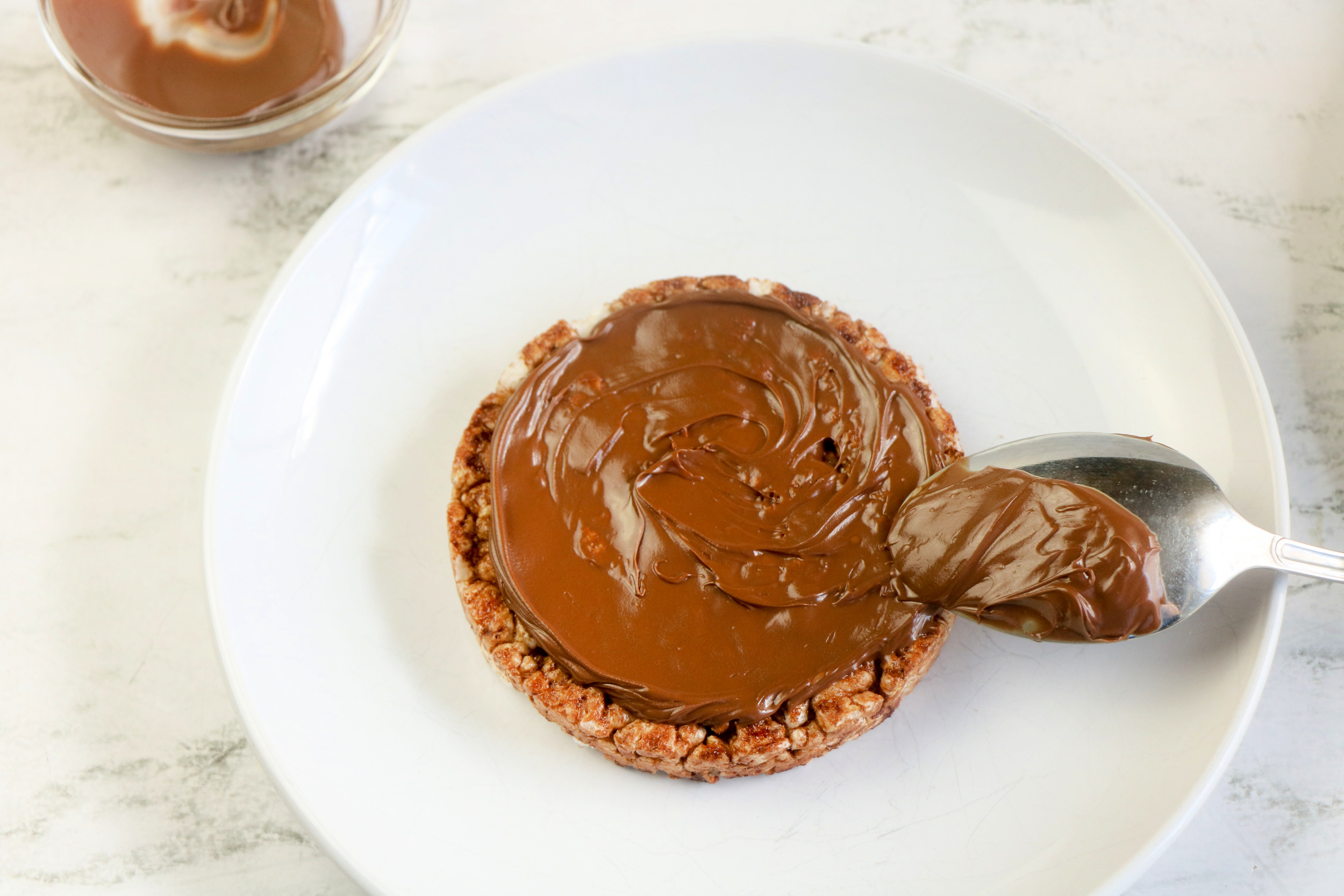 First, spread the hazelnut spread on the rice cake with a spoon.