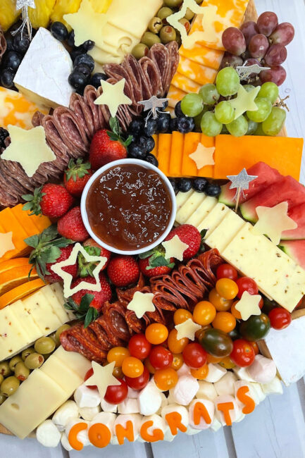 graduation party charcuterie board with the congrats made out of cheeses and cheese stars as well.