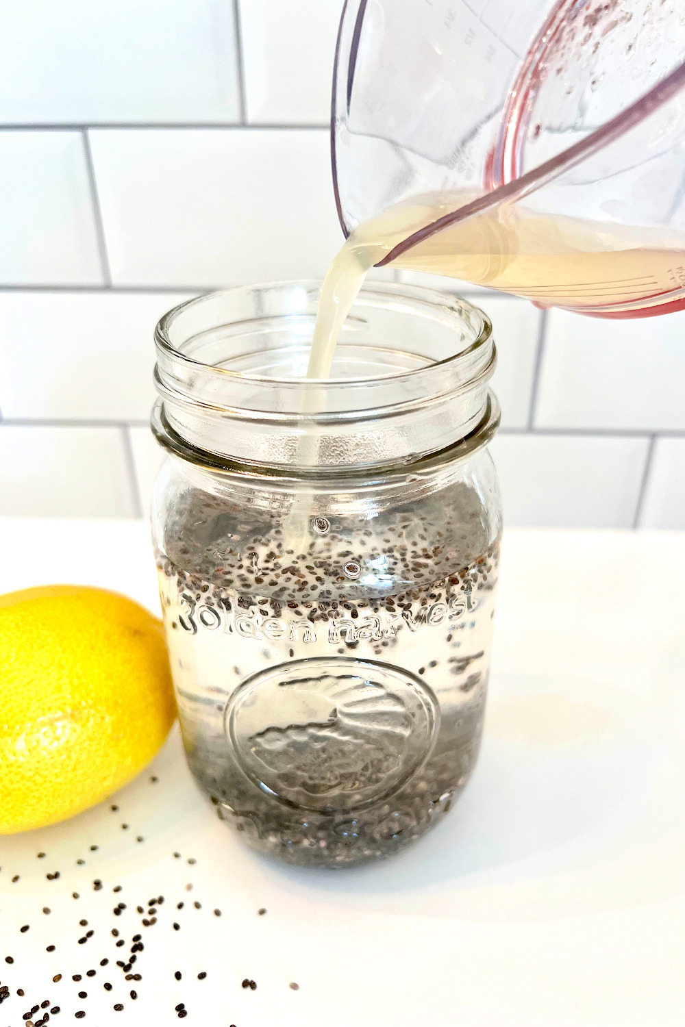 how to add chia seeds to make a chia seed detox water. Pouring lemon into the chia water.