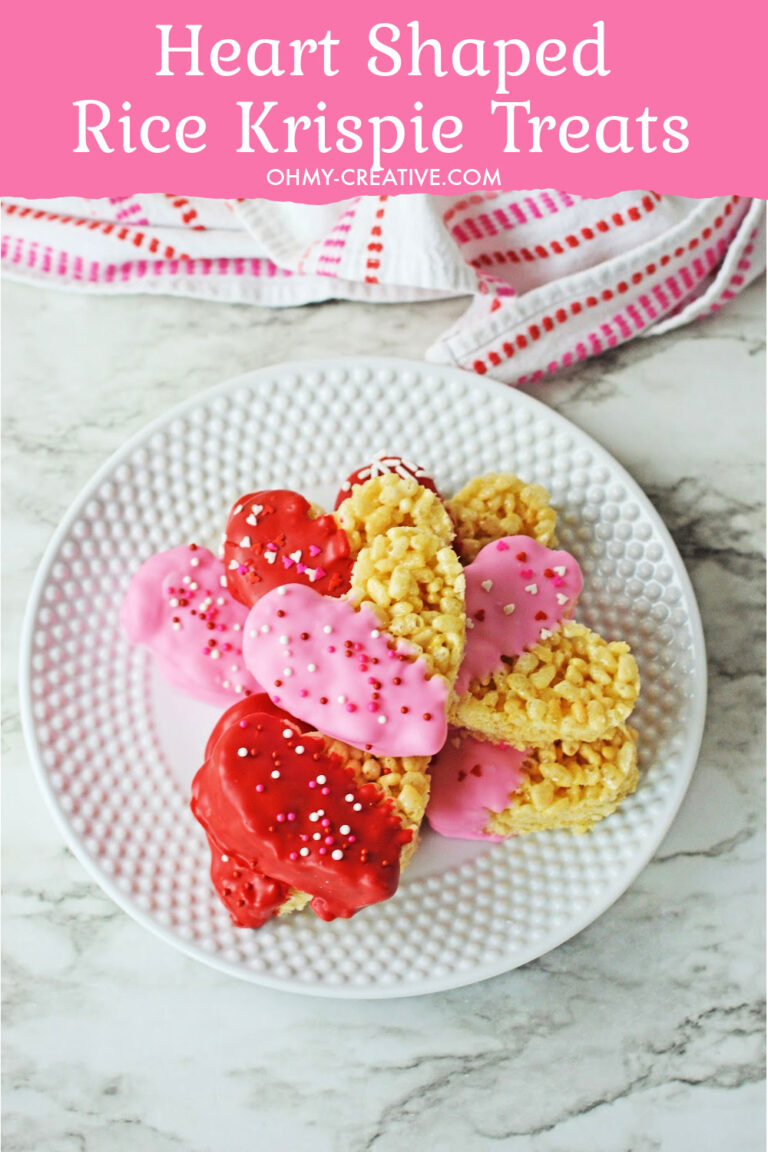 A white plate of heart shaped rice Krispie treats dipped in pink and red chocolate with sprinkles.