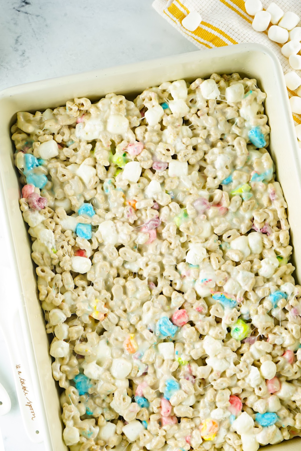 Lucky Charms Rice Krispie Treat mixture pressed out in a baking dish.