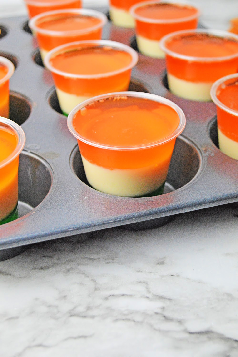 Layered St. Patrick's Day shots setting up in a muffin tin.