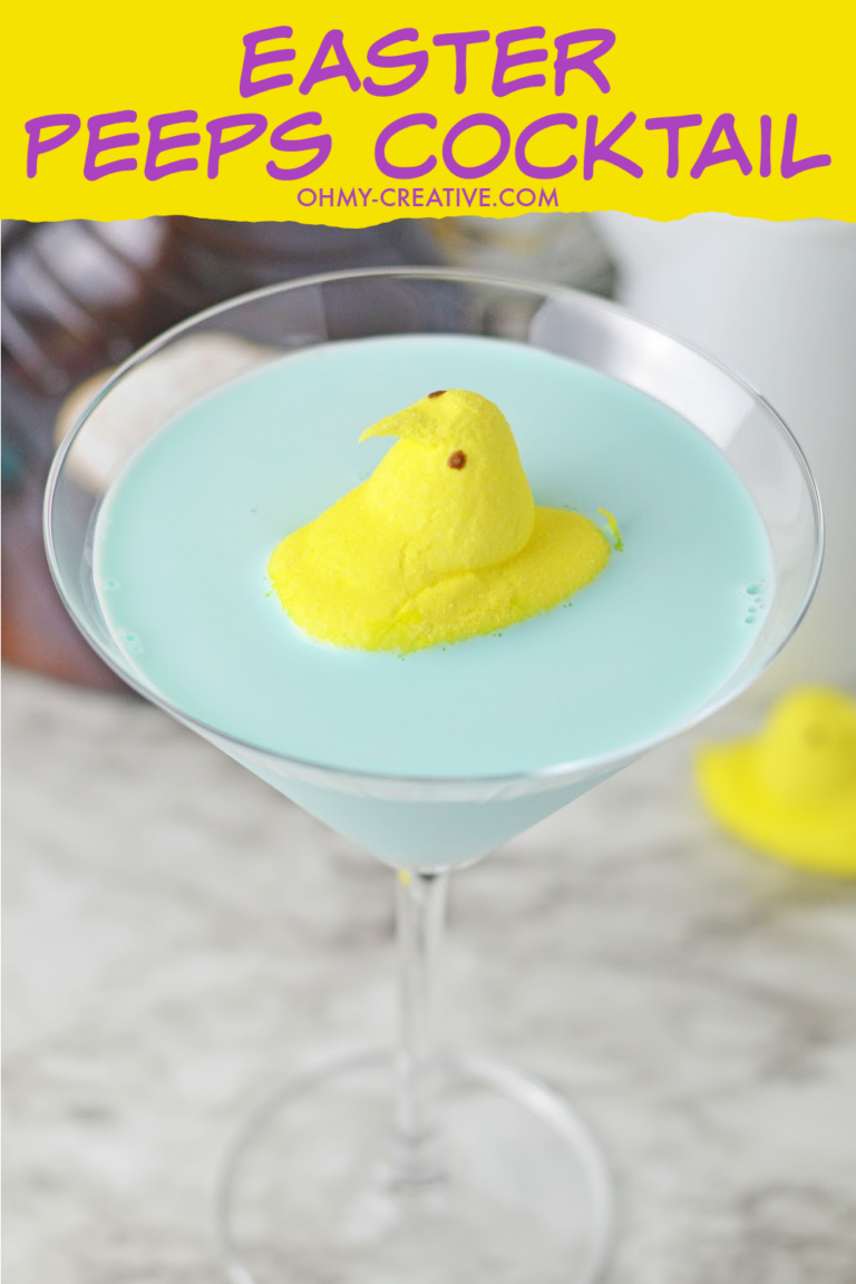 A colorful Easter Peeps cocktail martini that is blue with a yellow chick Peeps floating in the center.