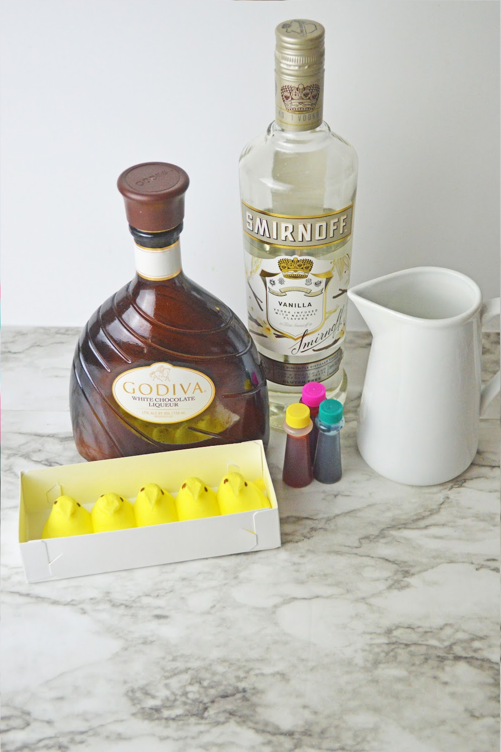 Ingredients to make a peeps cocktail martini including white Godiva liqueur, yellow peeps, cream, and vodka. 