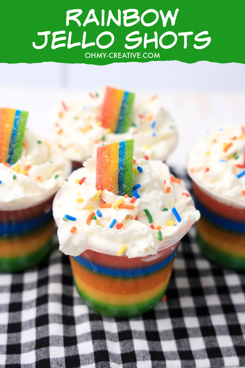 Rainbow jello shots topped with whipped cream, rainbow sprinkles and rainbow candy.