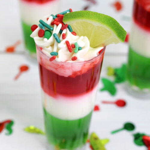 Layered Cinco de Mayo jello shots using the Mexican Flag colors; red, white and green. Topped with whipped cream and sprinkles.
