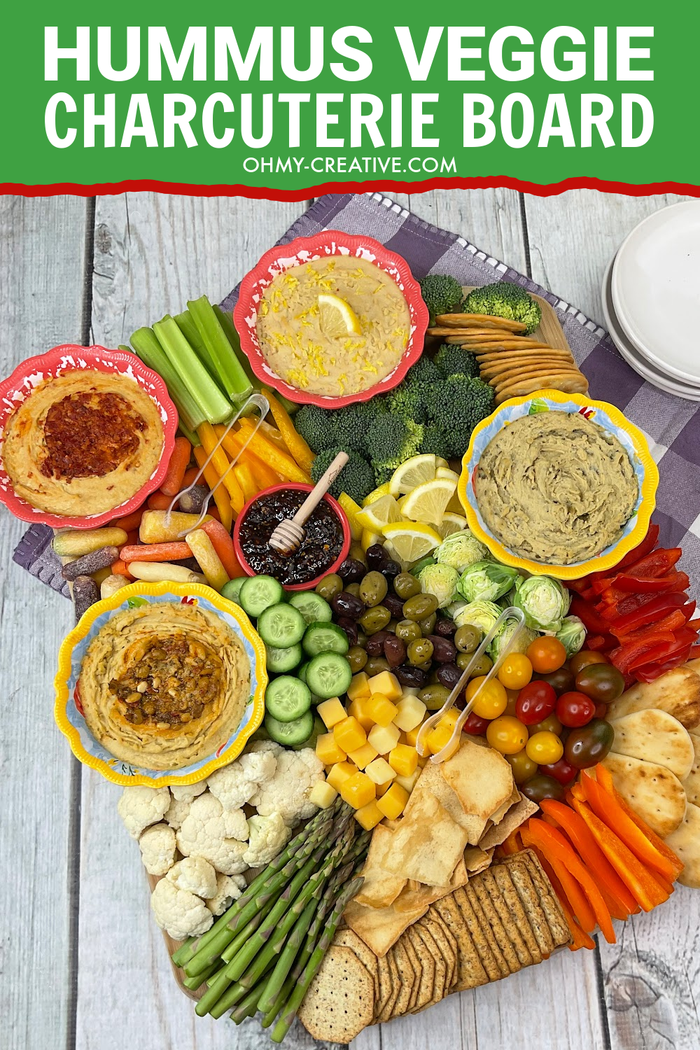 A healthy vegetable veggie charcuterie board that includes several bowls of hummus for dips.