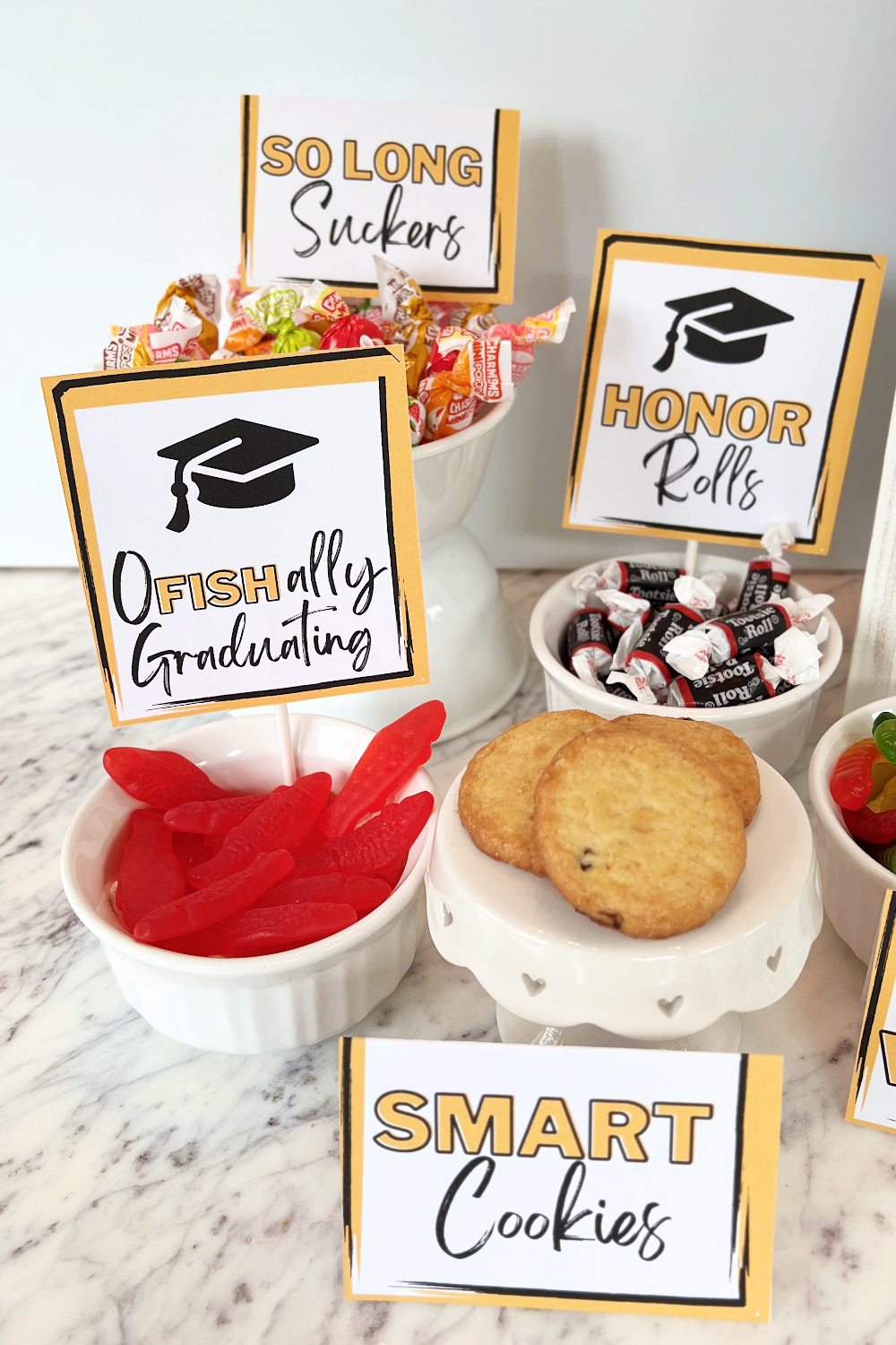 Several graduation candy bar signs displayed with bowls of candies.