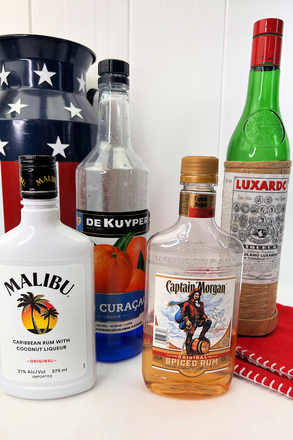 Bottles of Malibu Rum, Grenadine, Spiced Rum and Blue Curacao are the alcohol used in this patriotic cocktail.

