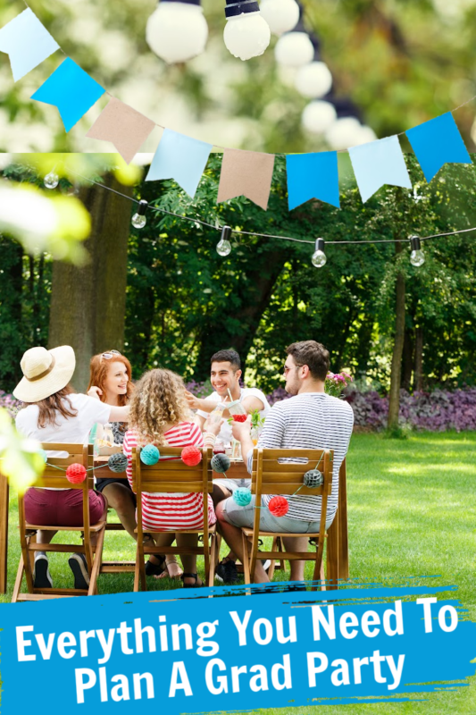 Graduates sitting under a tree at a table for a graduation party. Pinterest text and party garland.