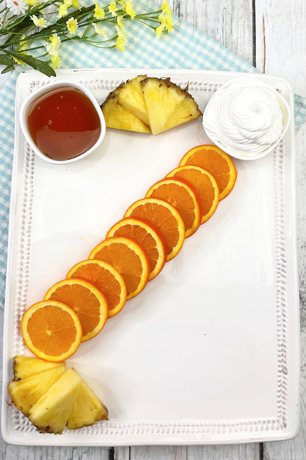 How to make a fruit platter or fruit charcuterie board. Start by placing sliced oranges across the center of the plater on a diagonal.